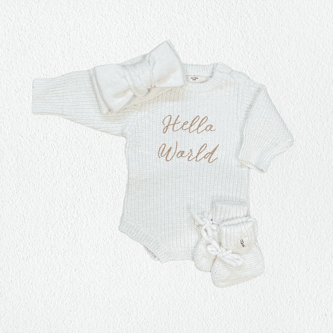 Hello World Coming Home Romper flat lay with matching cloud knit pom beanie and booties — Brave Little Lamb
