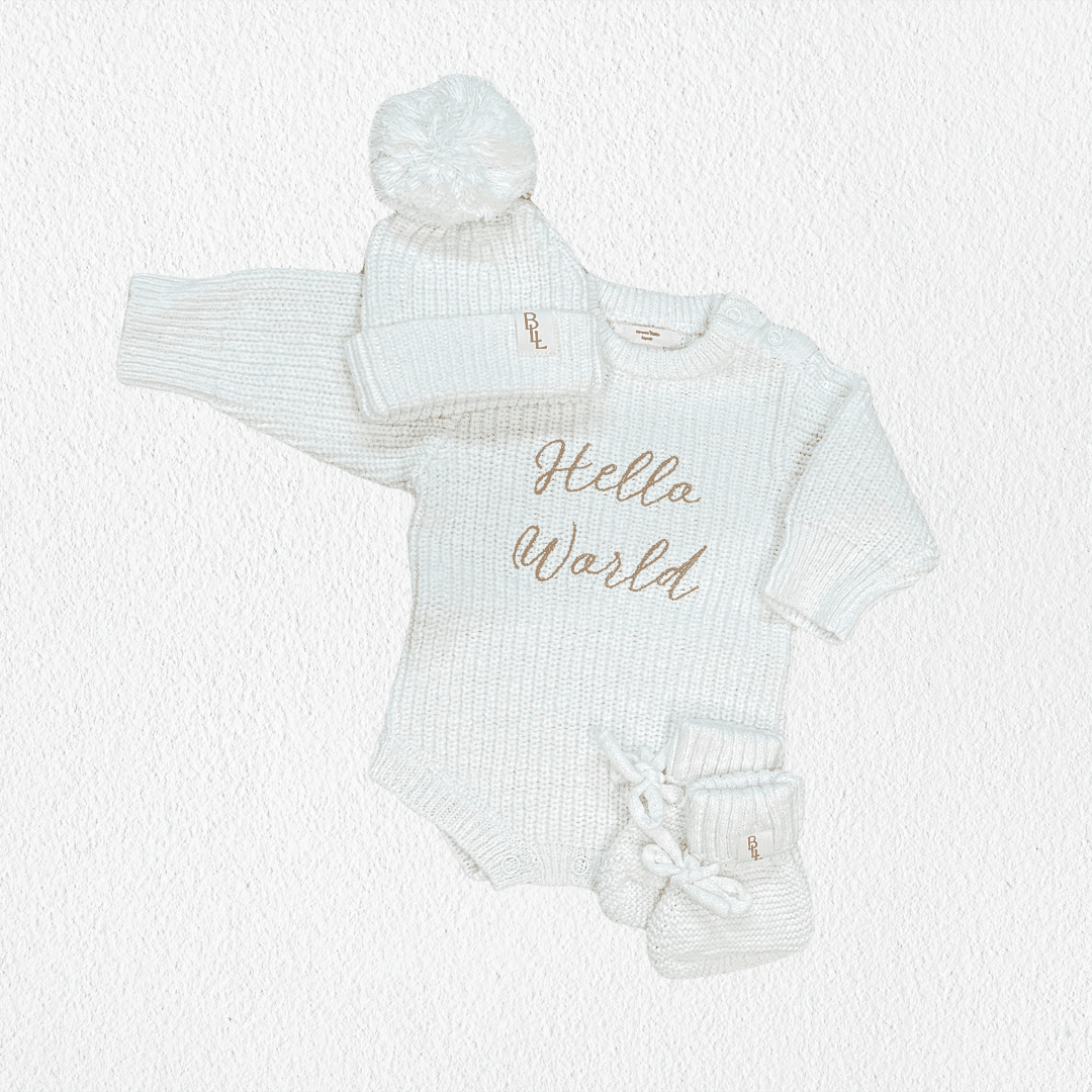 Hello World Coming Home Romper flat lay with matching cloud knit pom beanie and booties — Brave Little Lamb