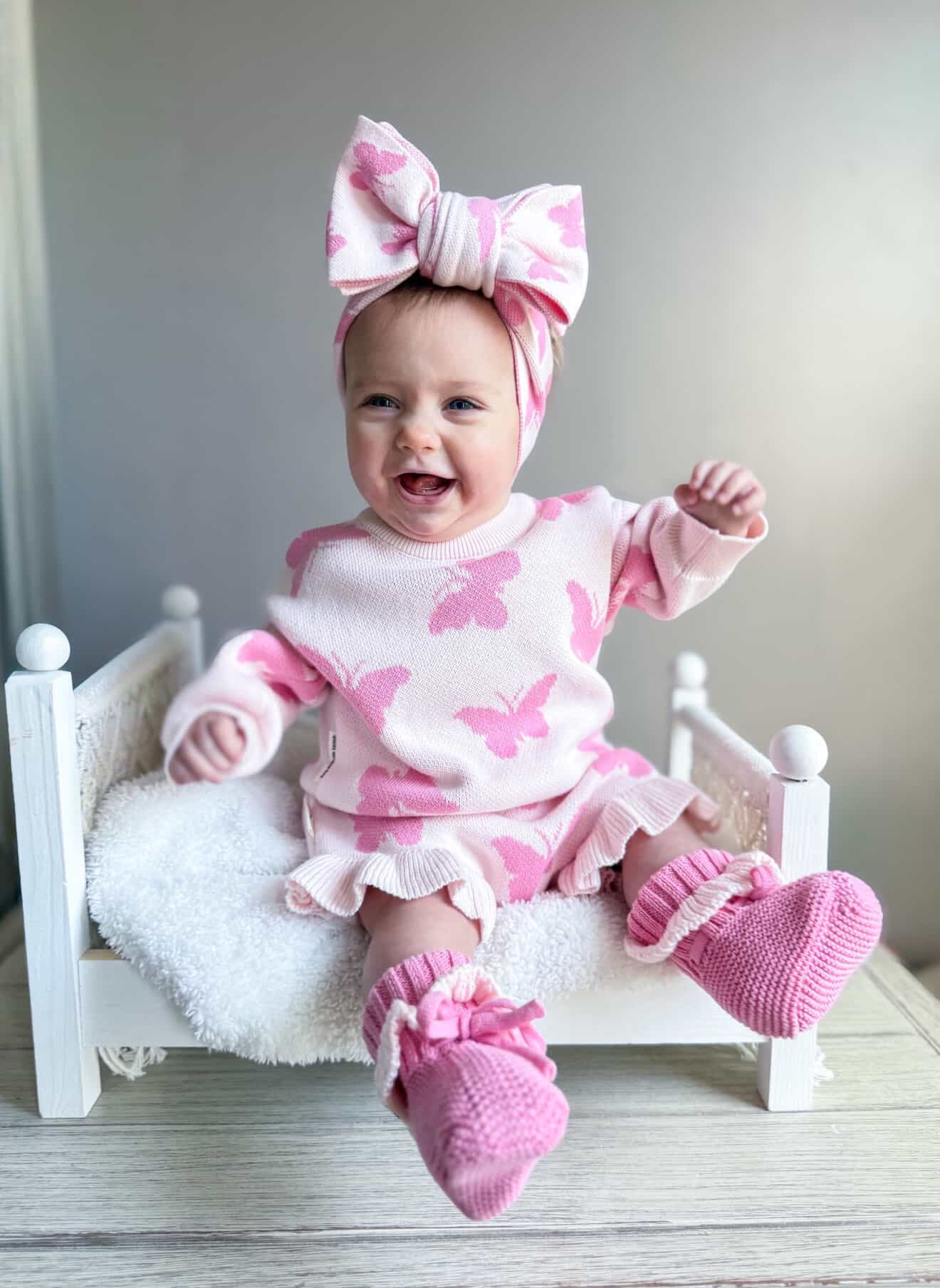Smiling baby wearing pink butterfly knit sweater set — Brave Little Lamb